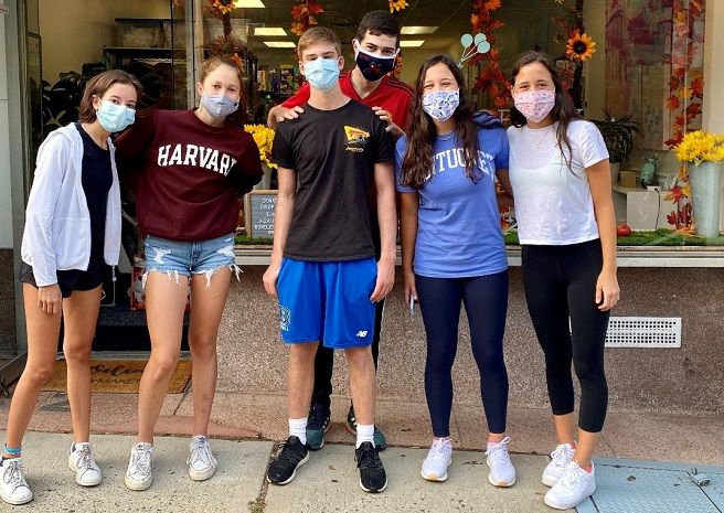 A small group of teen volunteers pose for a photo wearing facemasks.