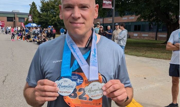 A man displays two medals after running a marathon.