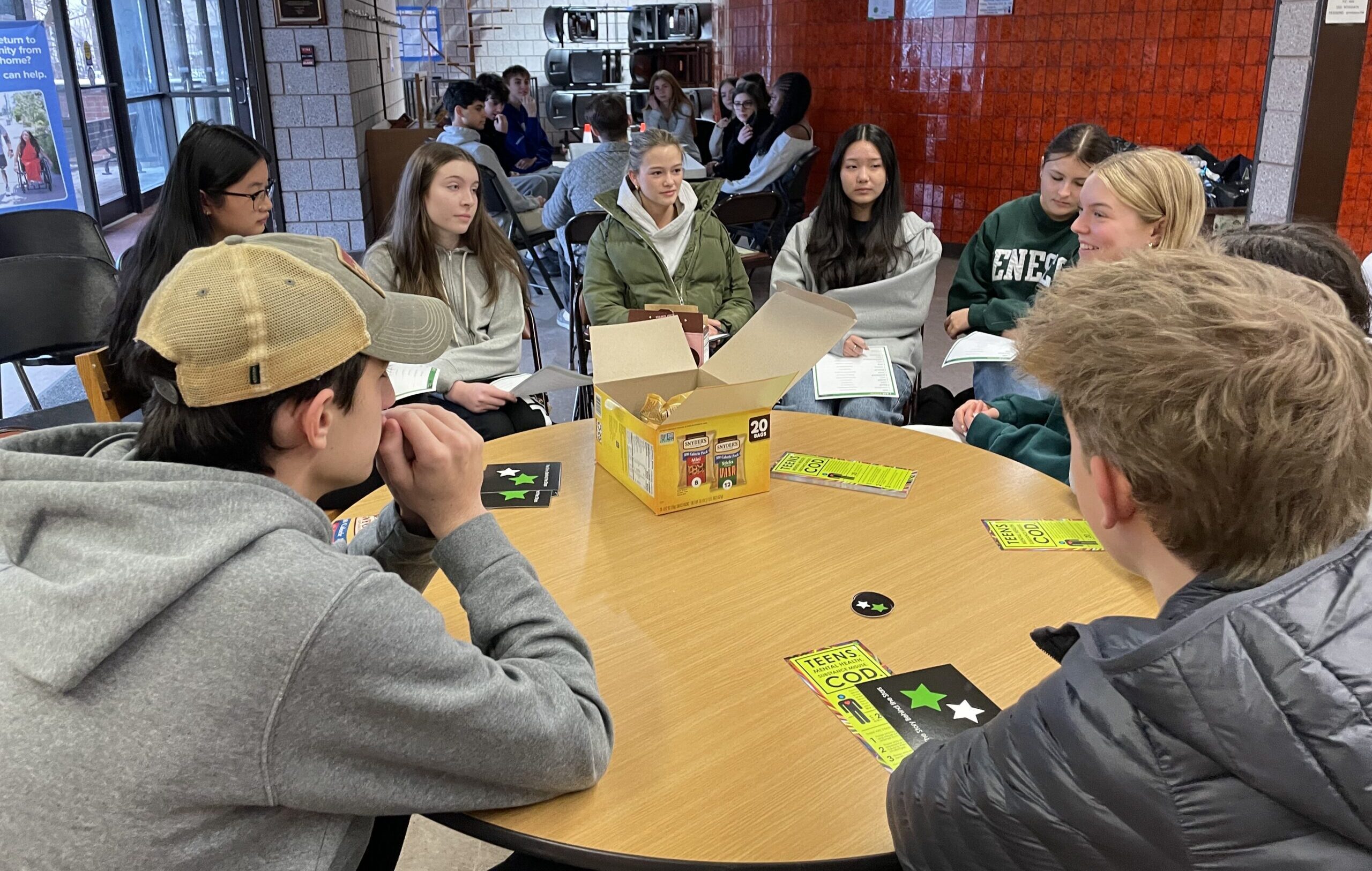 Groups of 8-10 teenagers sit at round tables in discussion groups.