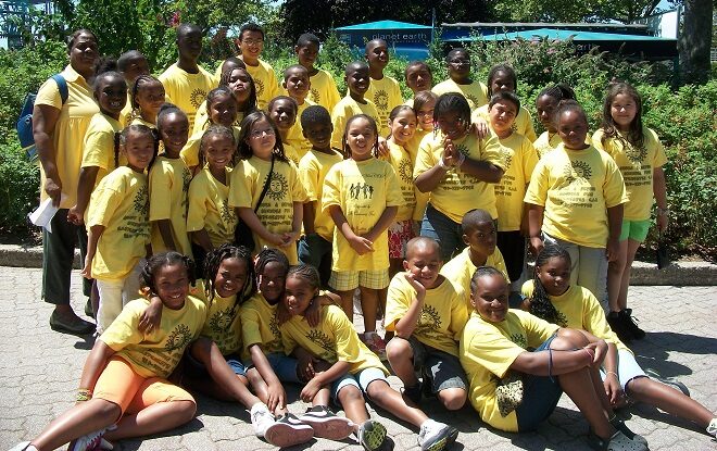 A group of school children with a variety of racial backgrounds pose for a group photo during a summer program event.