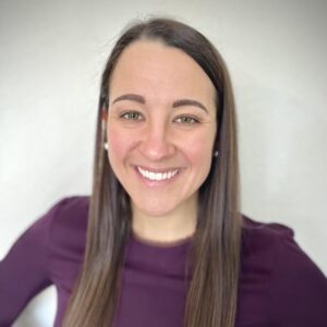 Photo of a White female with brown hair wearing a deep berry colored top.