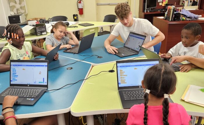 20250728_095603 (1) copy Elementary school participants work with a Youth Community Fund volunteer during an afterschool program.