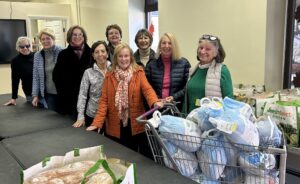 A group of female volunteers deliver Thanksgiving groceries to a community center.