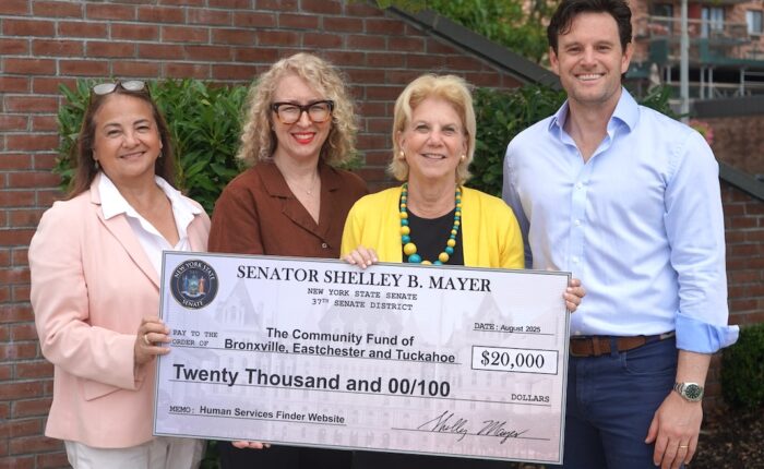 Photo of three women and one man posing for a photo, holding a facsimile of a check representing a grant.