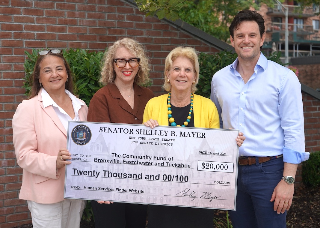 Photo of three women and one man posing for a photo, holding a facsimile of a check representing a grant.