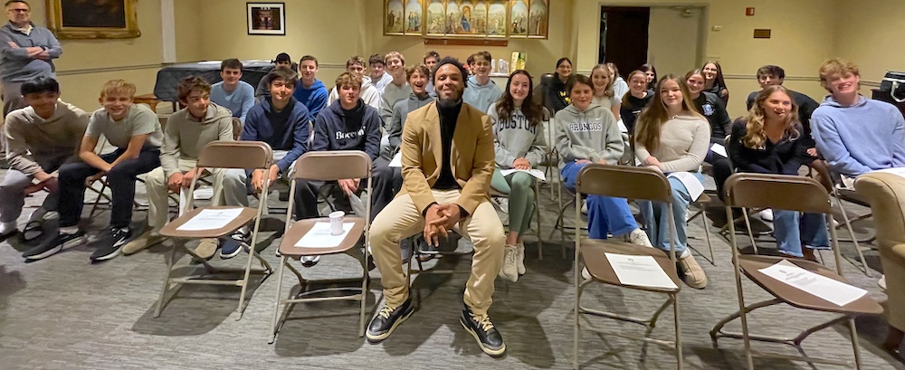 A group photo of several teens and a guest speaker. Everyone is smiling.