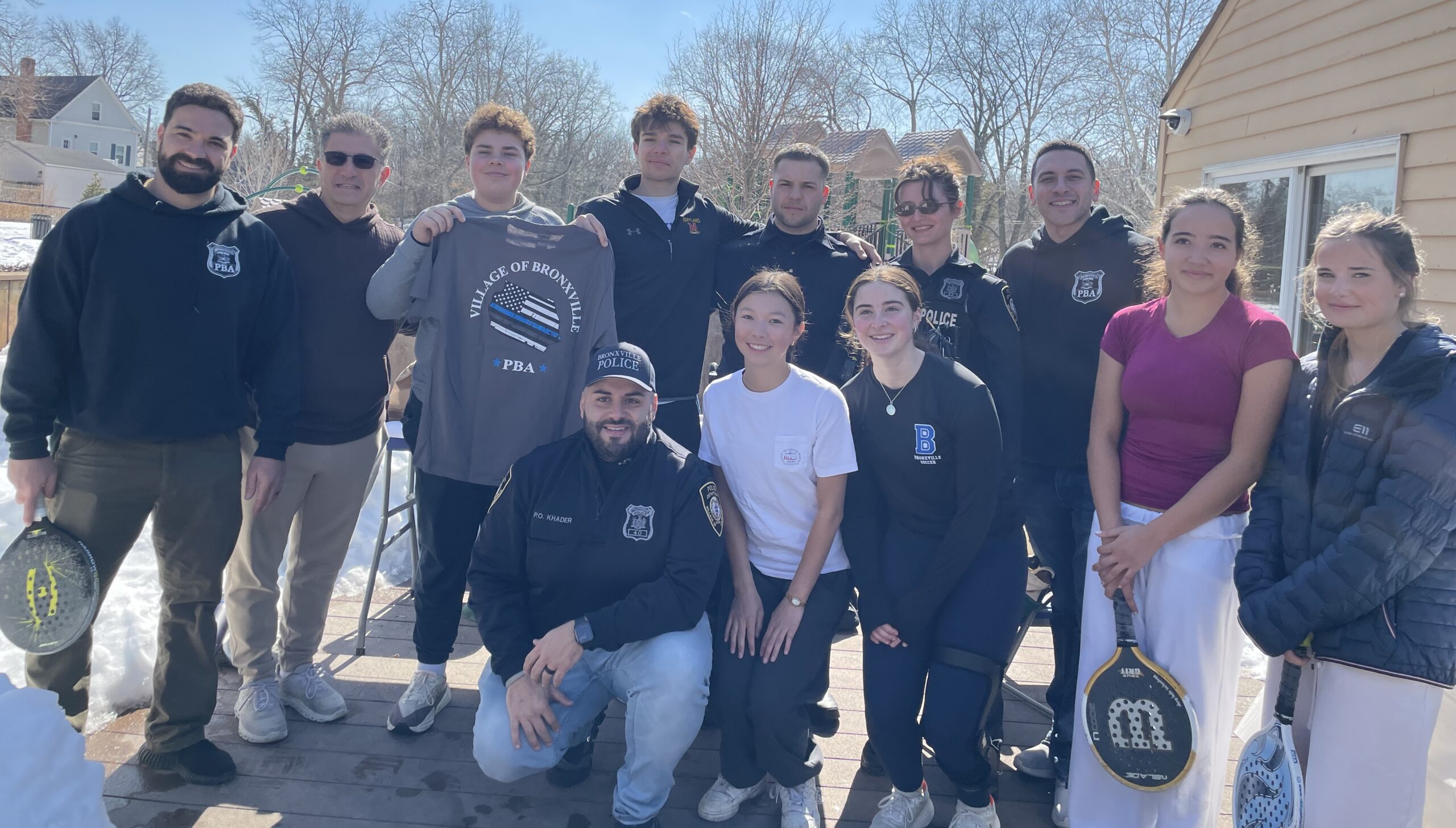 Group photo of teens and police officers at a paddleball tournament.